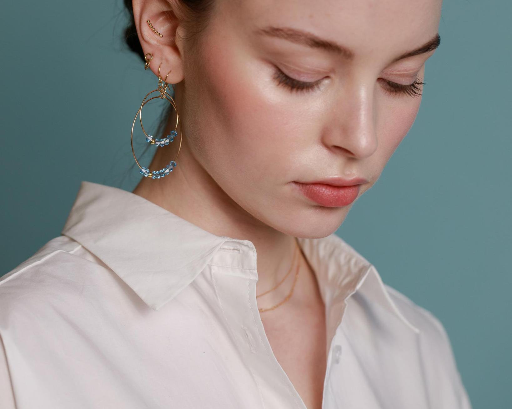 A pair of gold-filled hoop earrings with aquamarine crystals.