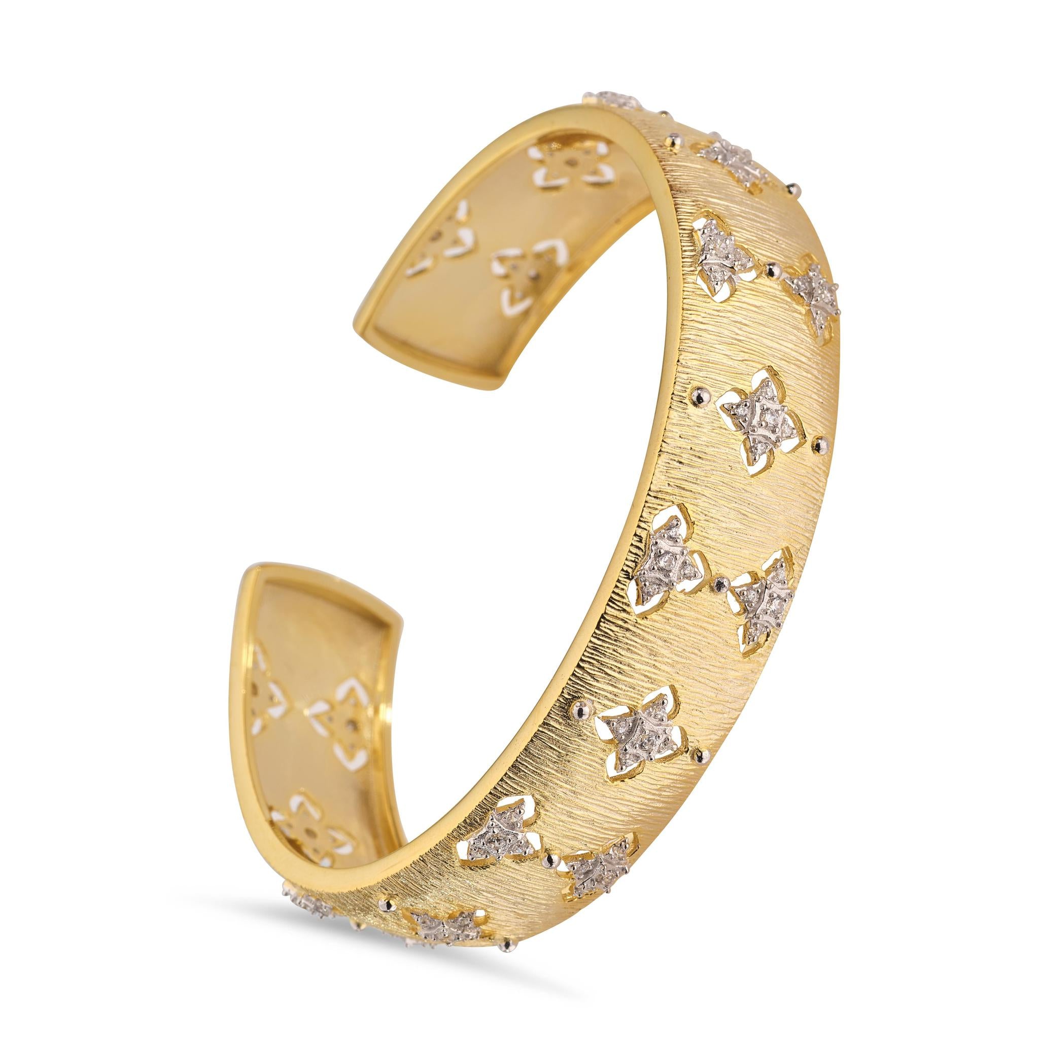 A gold-plated bangle bracelet with a floral pattern and small, inset stones.