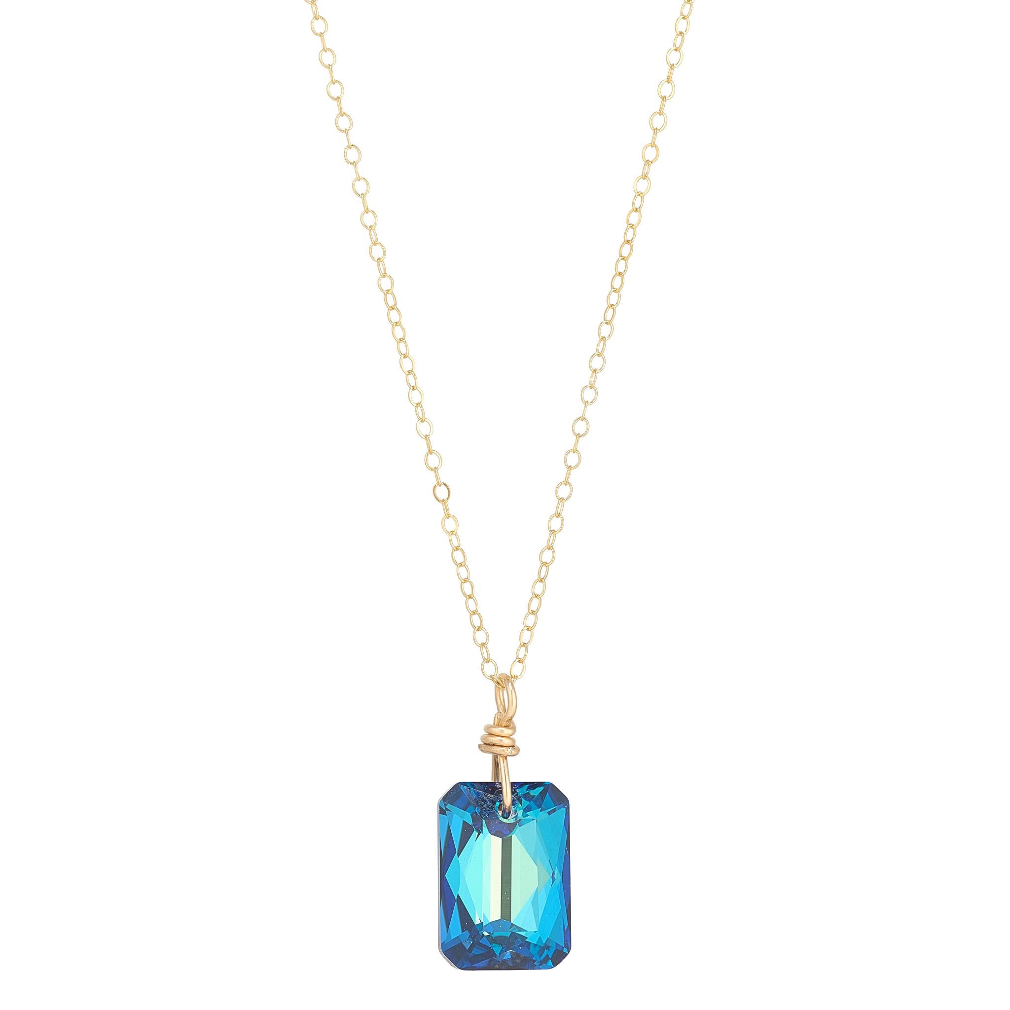 A gold filled chain necklace with a large emerald cut blue crystal pendant.