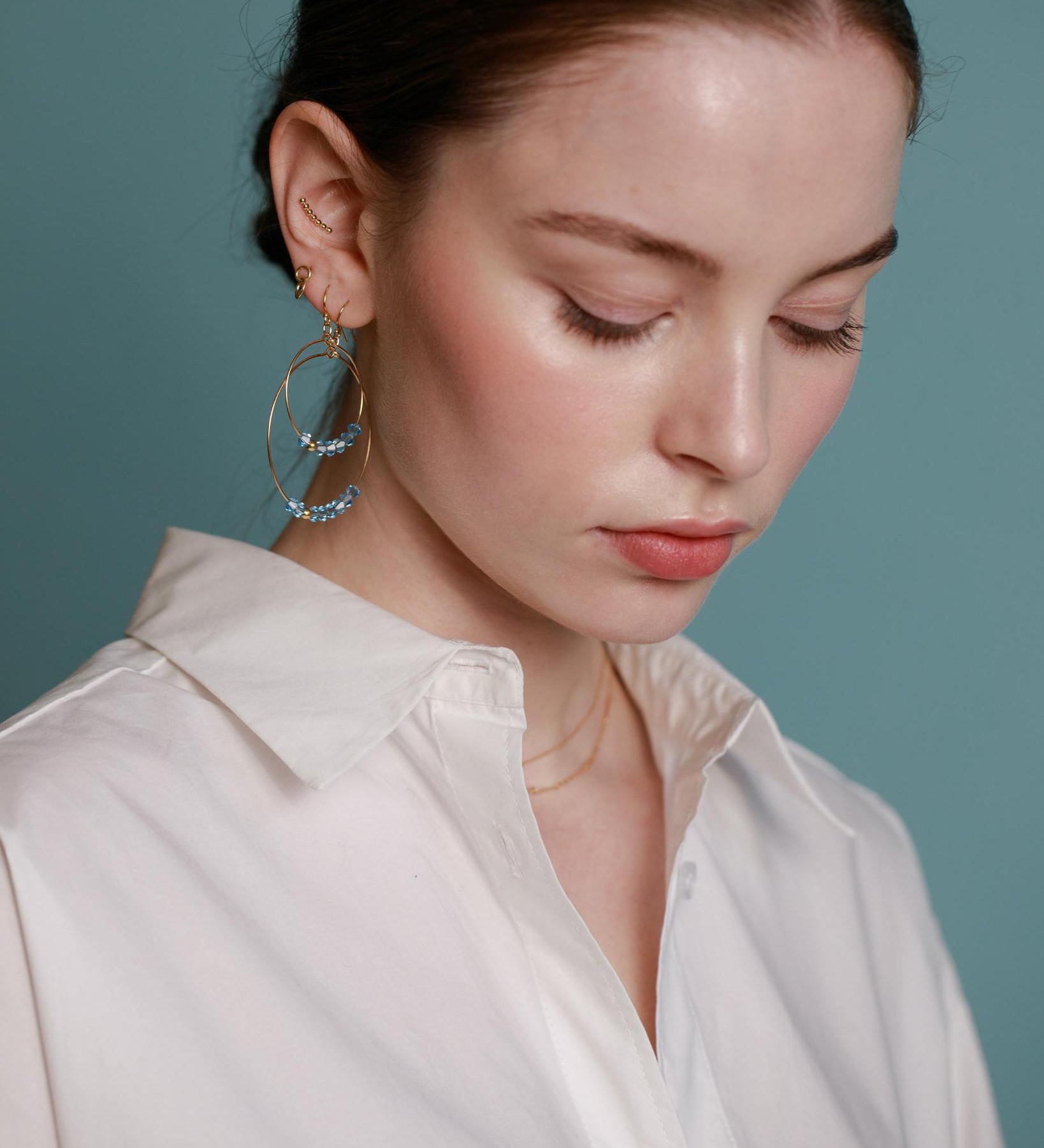 A pair of gold-filled hoop earrings with aquamarine crystals.