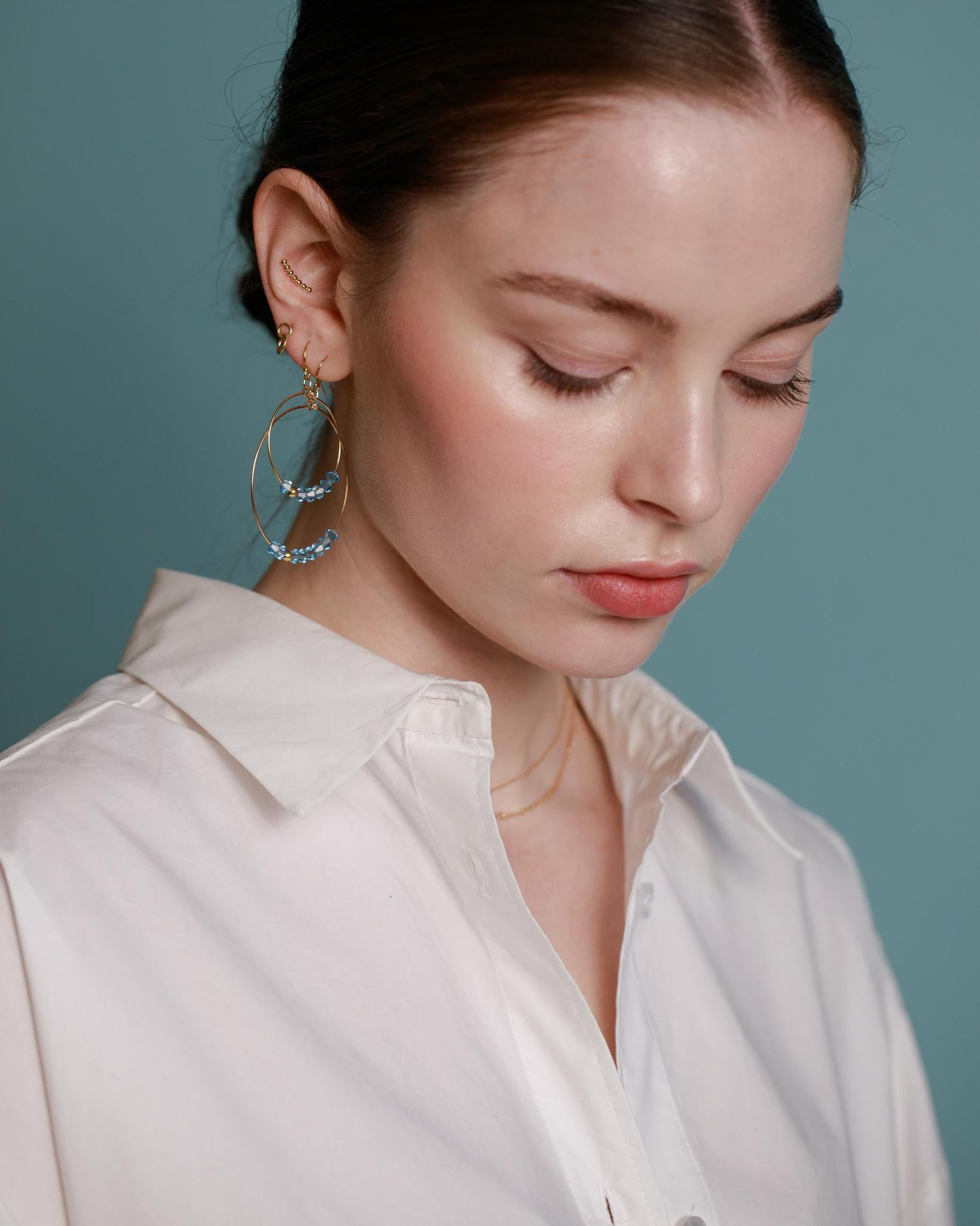 A pair of gold-filled hoop earrings with aquamarine crystals.