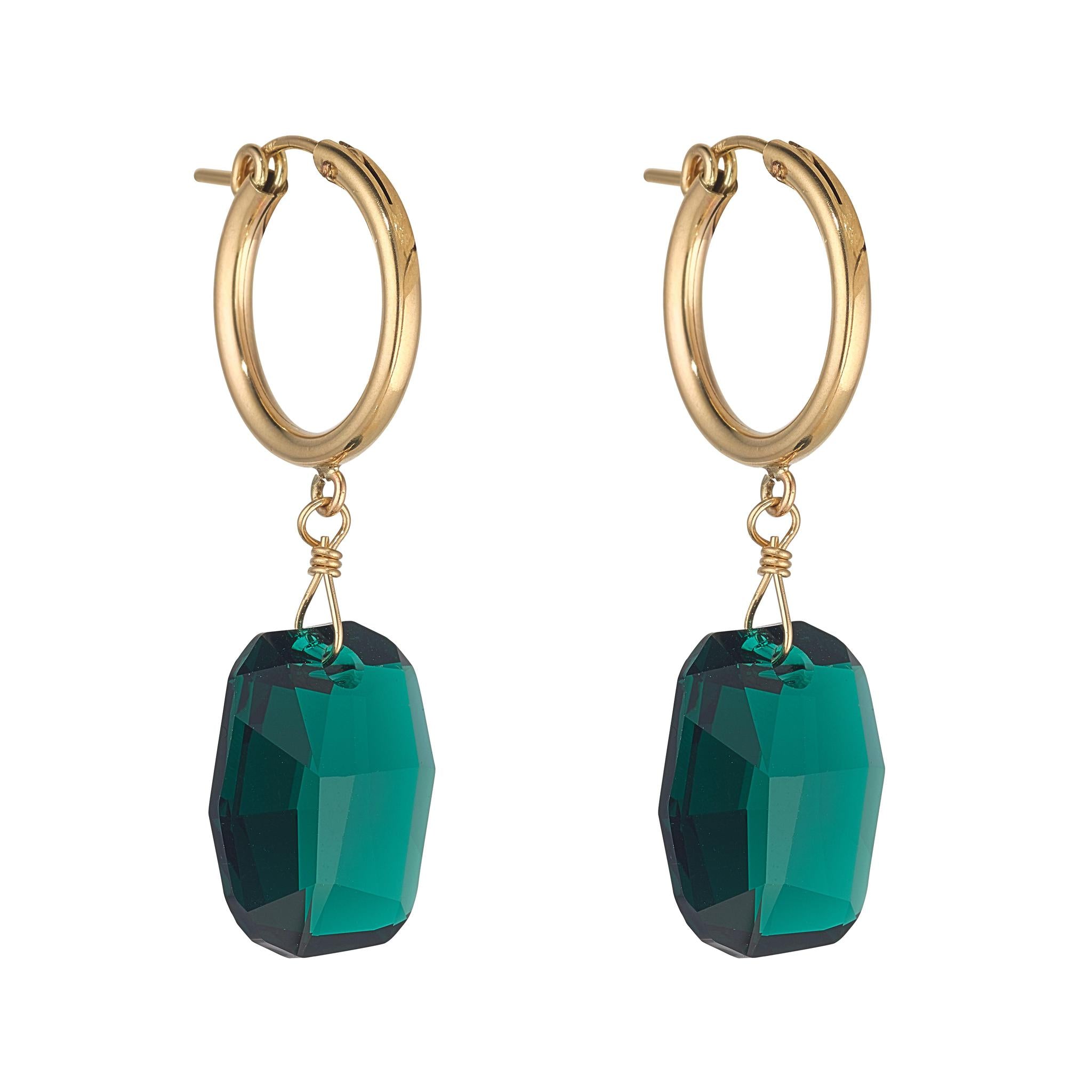 A pair of gold-filled clip hoop earrings with large emerald green crystals attached.