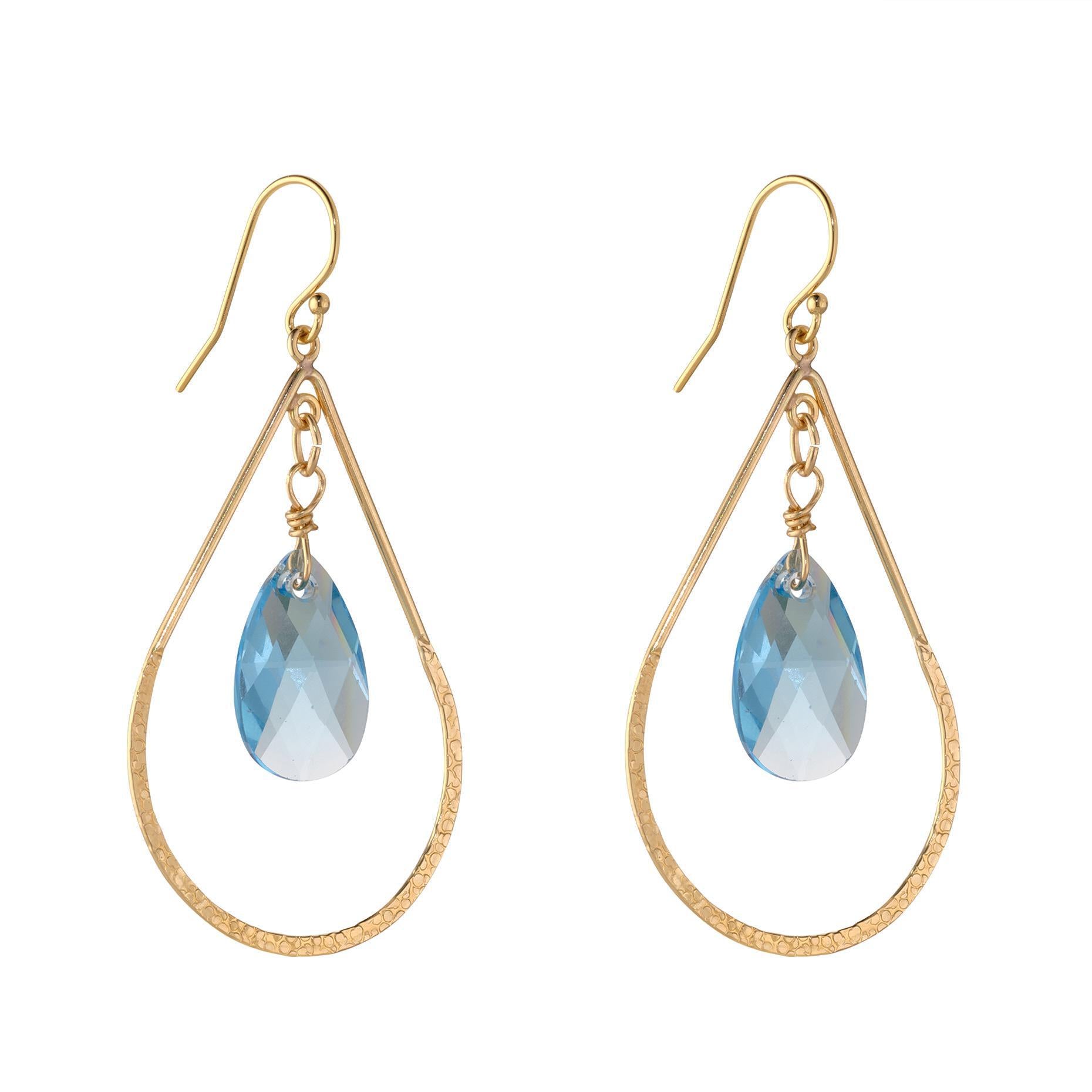 A pair of gold-filled earrings featuring hammered teardrop shapes with blue aquamarine crystals at the bottom.