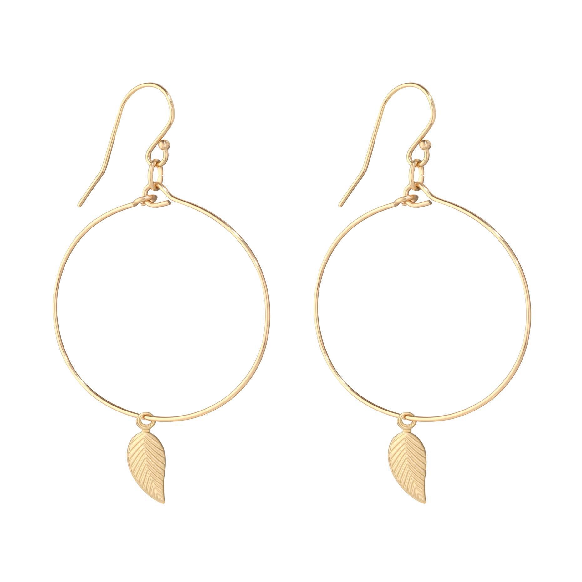 A pair of gold-filled hoop earrings with a leaf design dangle from the hoop.