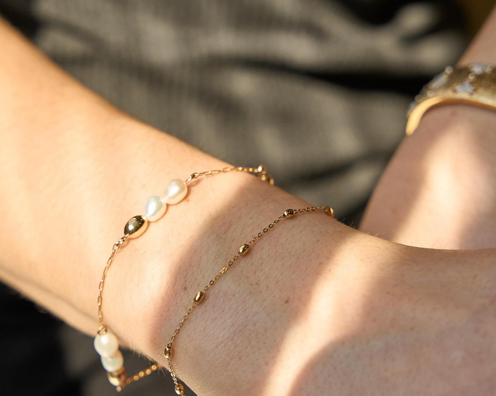 Close-up of a wrist with pearl bracelet and gold bracelet.