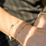 Close-up of a wrist with pearl bracelet and gold bracelet.