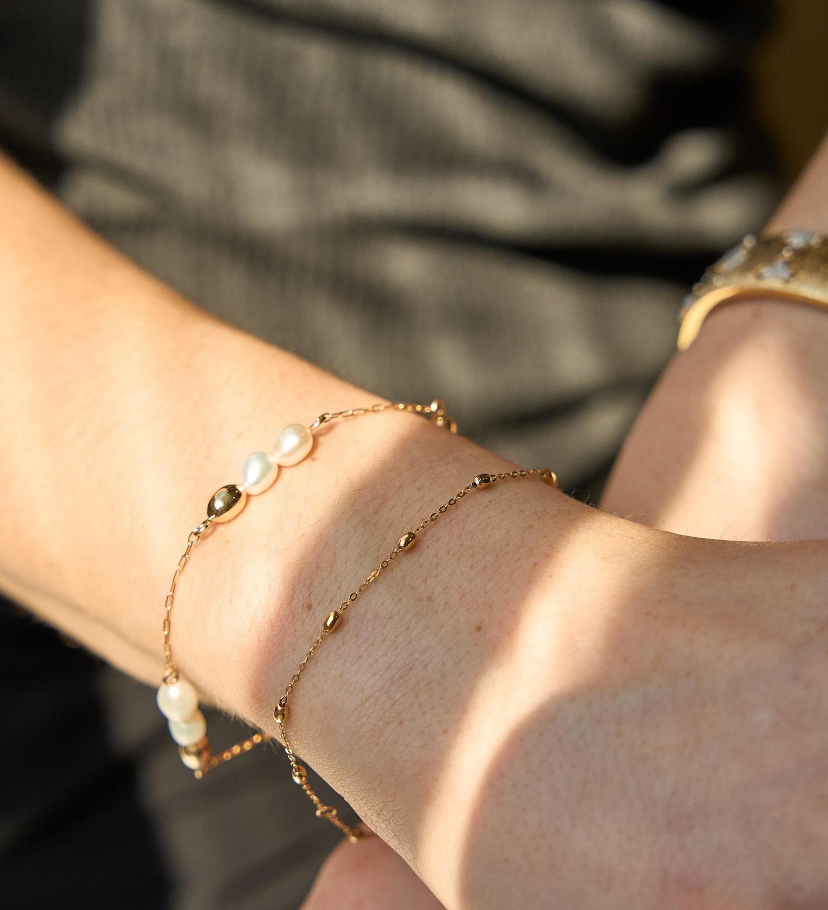 Close-up of a wrist with pearl bracelet and gold bracelet.