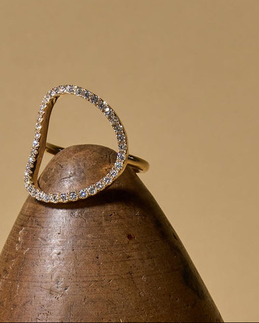 Two diamond rings on a brown surface with a wooden object in the background