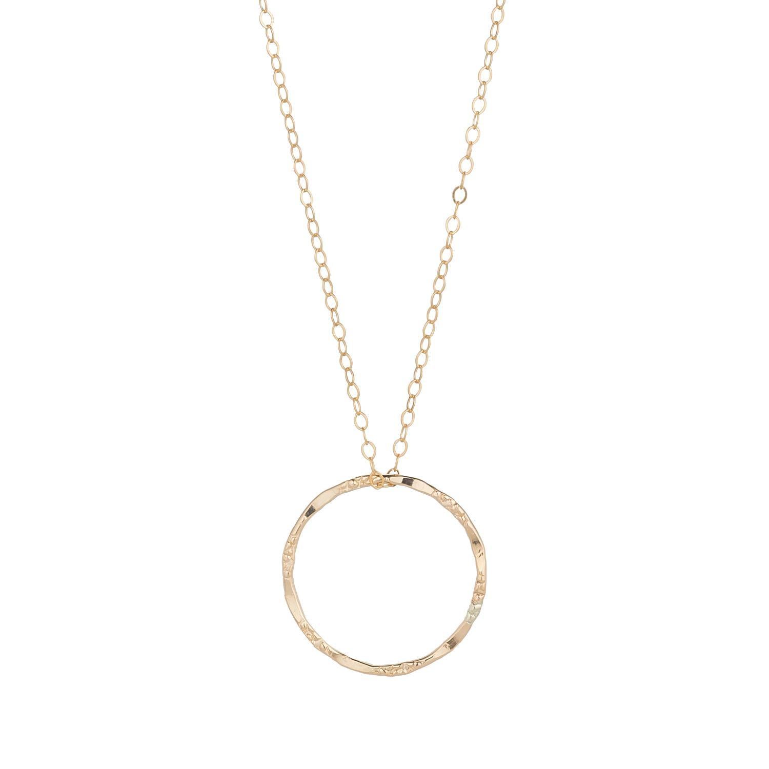 A gold filled necklace with a large molten circle pendant on a chain.