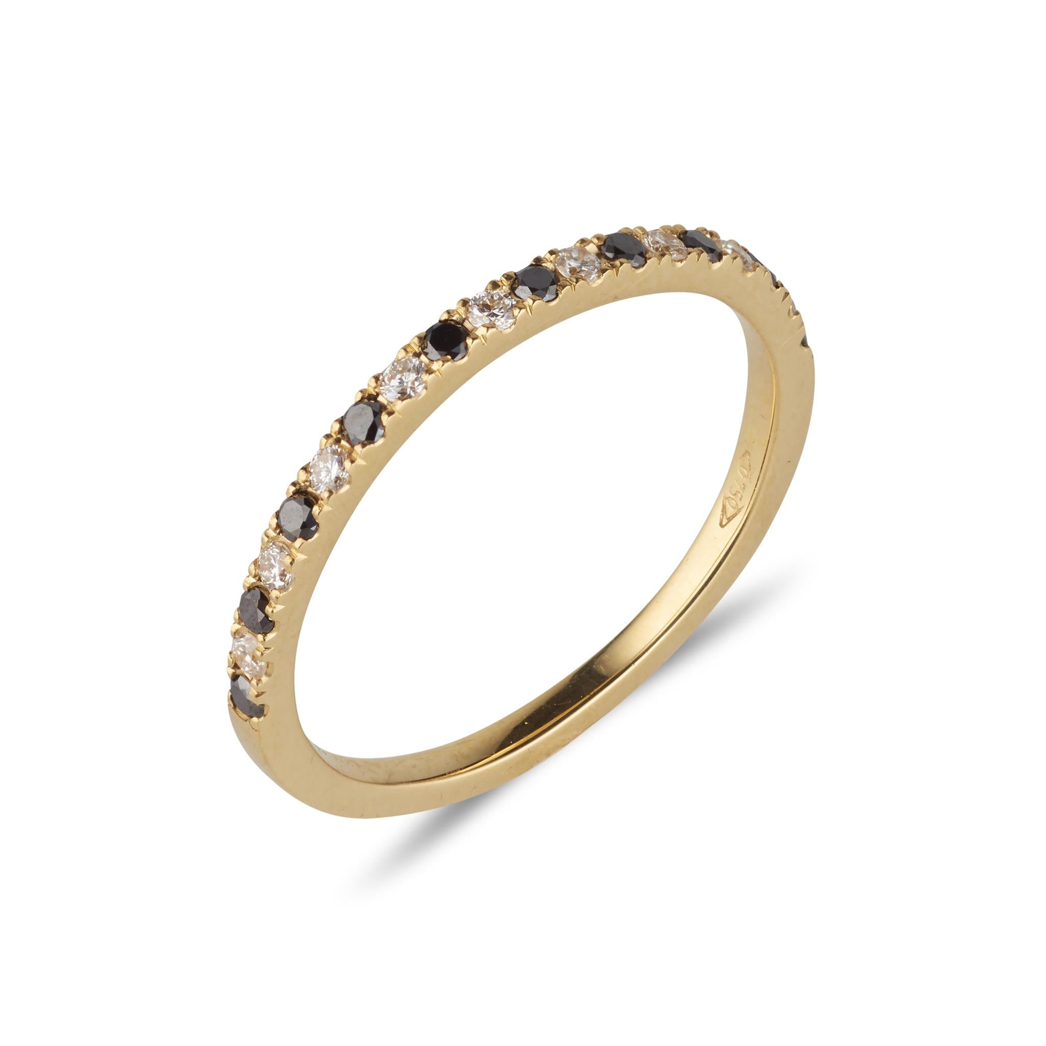A dainty diamond half eternity ring with black and white diamonds set in an 18kt yellow gold band.